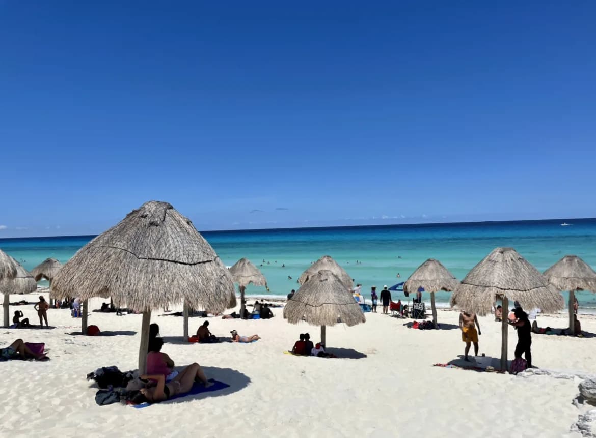 Palapas on a white sand beach with a Tripio group